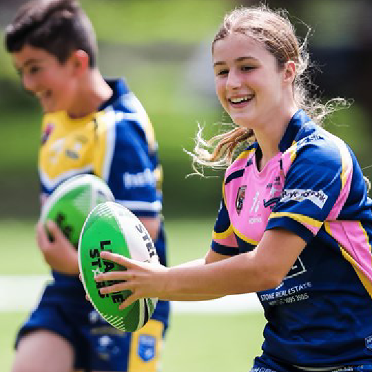 Young people holding rugby ball smiling while running